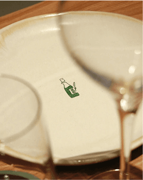 Close-up of a ceramic plate with a green wine bottle illustration at the center.